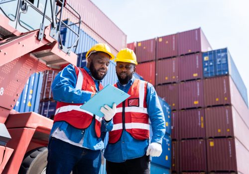 Two male engineers in a container shipping company Consulting to check the order for the container that is responsible